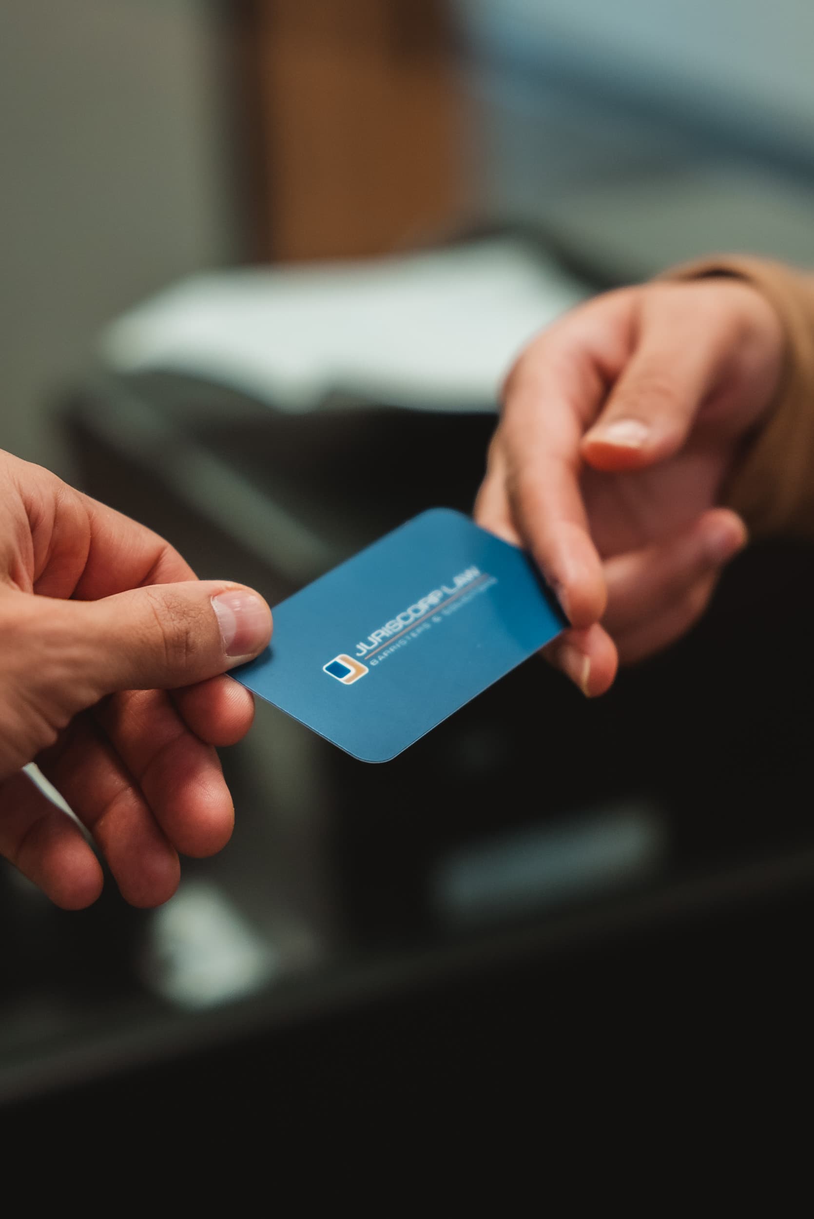 A Juriscorp Law business card being exchanged with a client