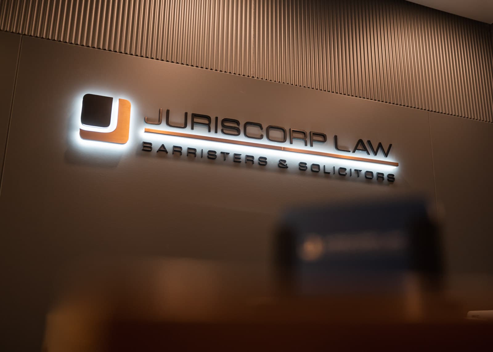 Illuminated Juriscorp Law wall sign inside the Edmonton office